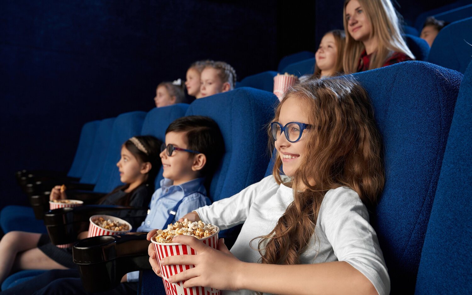 Niños viendo películas en el cine, sosteniendo cubos de palomitas de maíz.